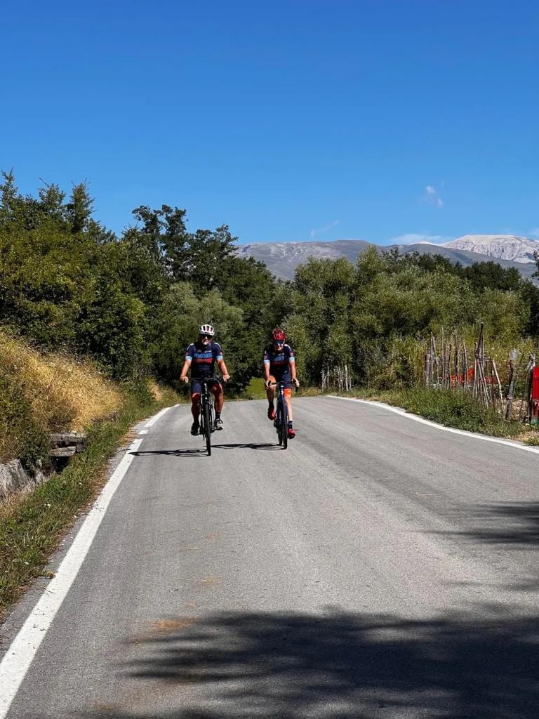 Two cyclists riding toward camera on Abruzzo mountain road